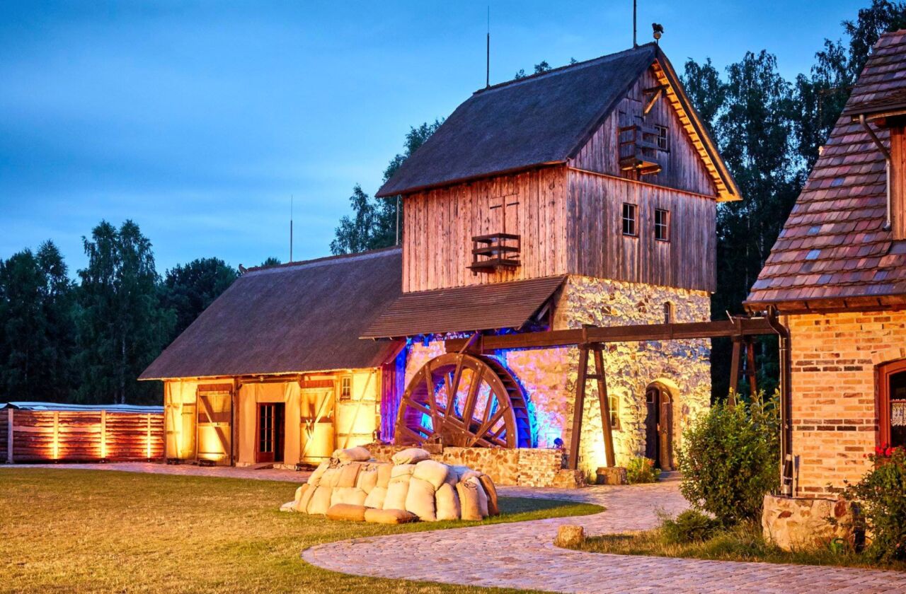 Das Bild zeigt die Krabat Mühle beleuchtet am Abend.