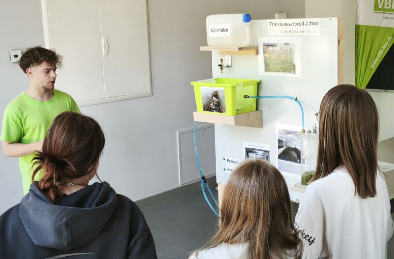 Ein VBH-Auszubildender erklärt Schülern an einem Modell die Wasseraufbereitung.