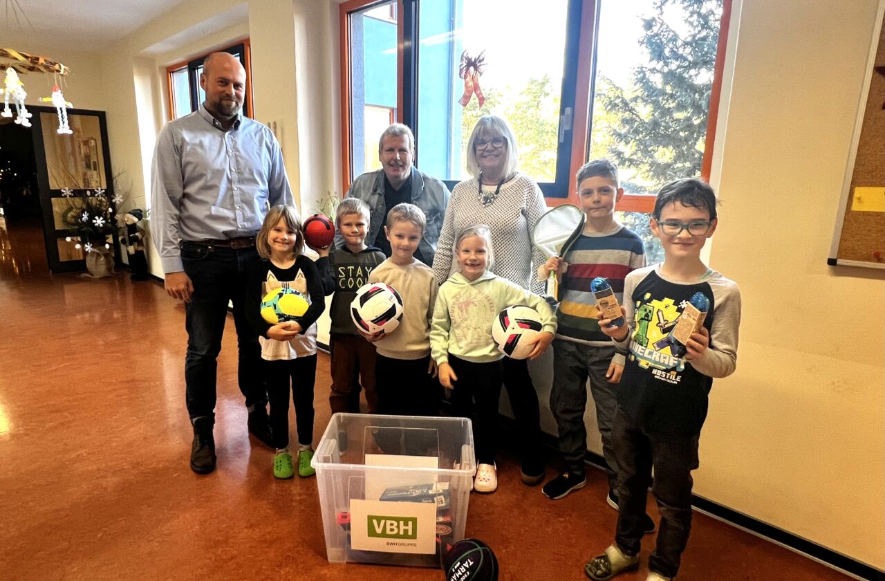 Schüler der 1. und 2. Klasse der Grundschule Burgneudorf freuen sich gemeinsam mit Schulleiterin Karin Weiß (m.) und Frank Richter (2.v.l.), Vertreter des Kindersprints, über die VBH-Sportmaterialkiste, die VBH-Prokurist Jan Schulze (l.) übergab.